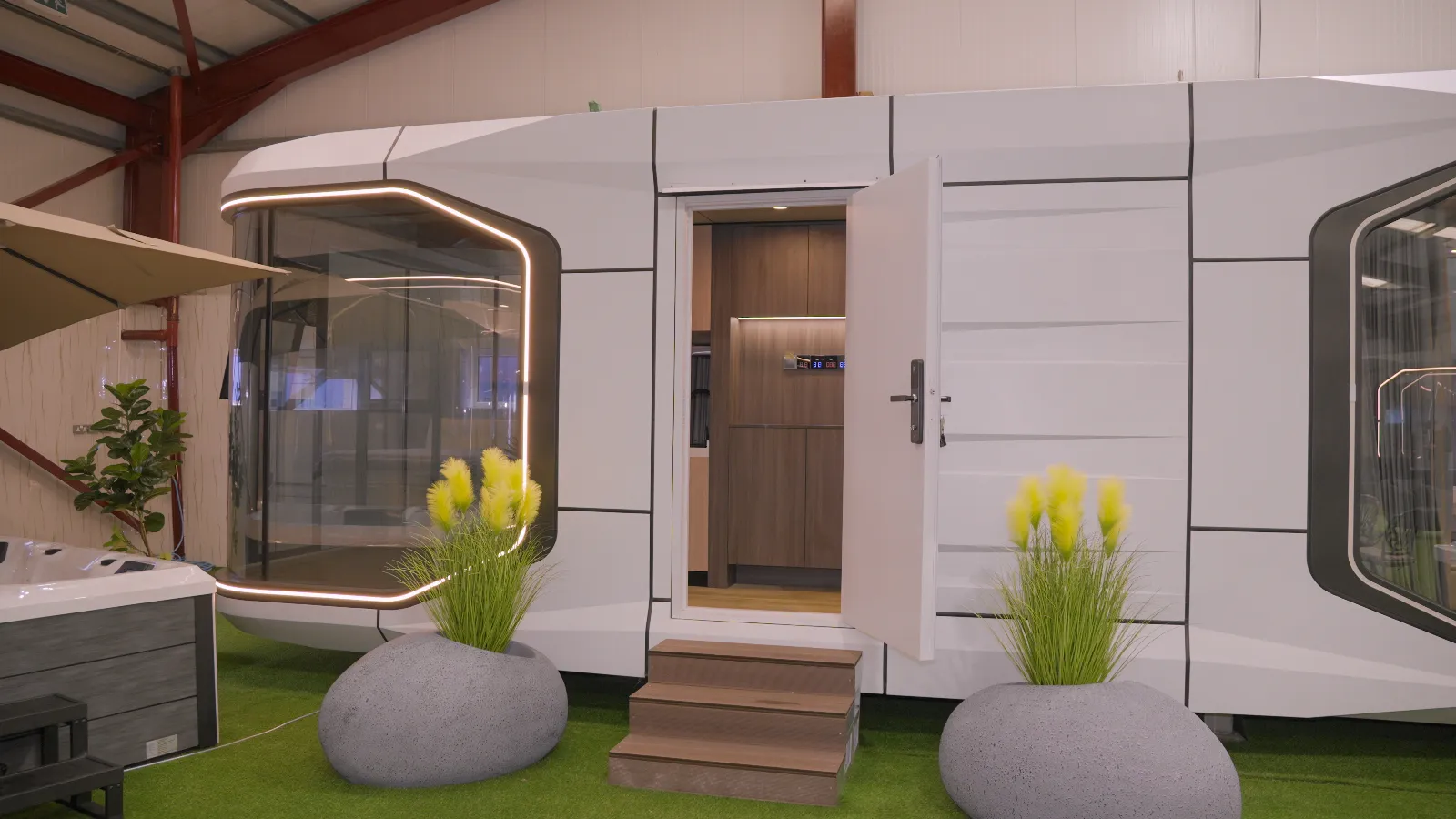 Pod home with its front door open, timber steps and planters outside